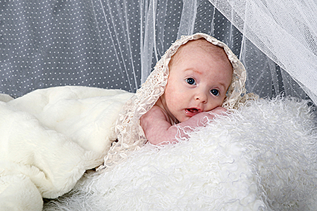 Bébé photographié sur un coussin blanc par Rachel Joubi